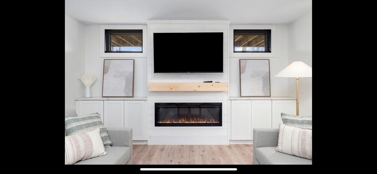 A living room with a fireplace and a flat screen tv on the wall.