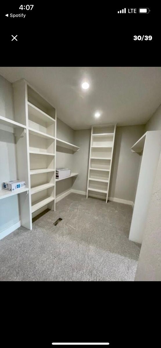 A walk in closet with lots of shelves and a ladder.
