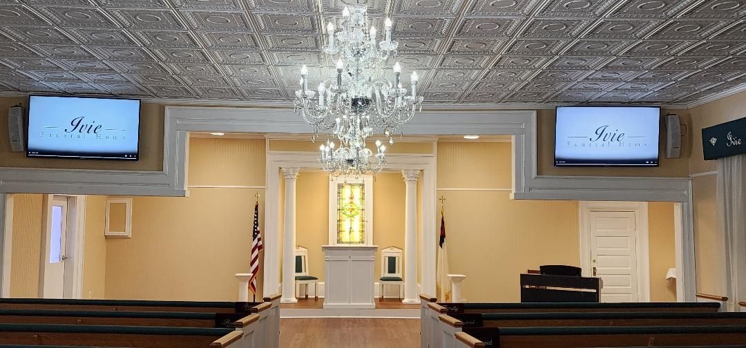 A church with a chandelier and two televisions on the ceiling.