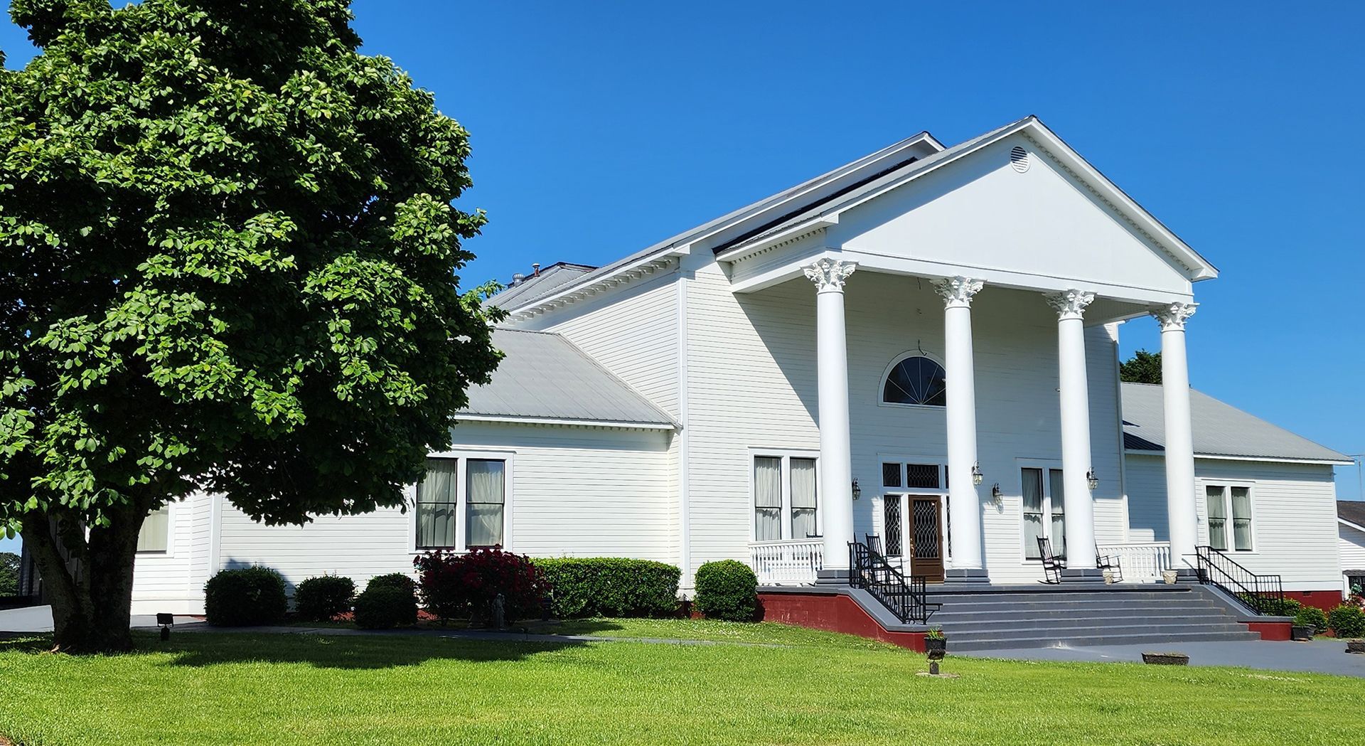 A large white building with columns and a tree in front of it