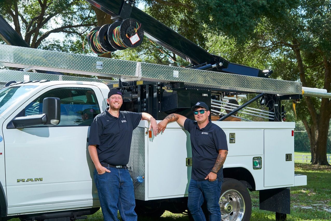 Two men are standing next to a utility truck.