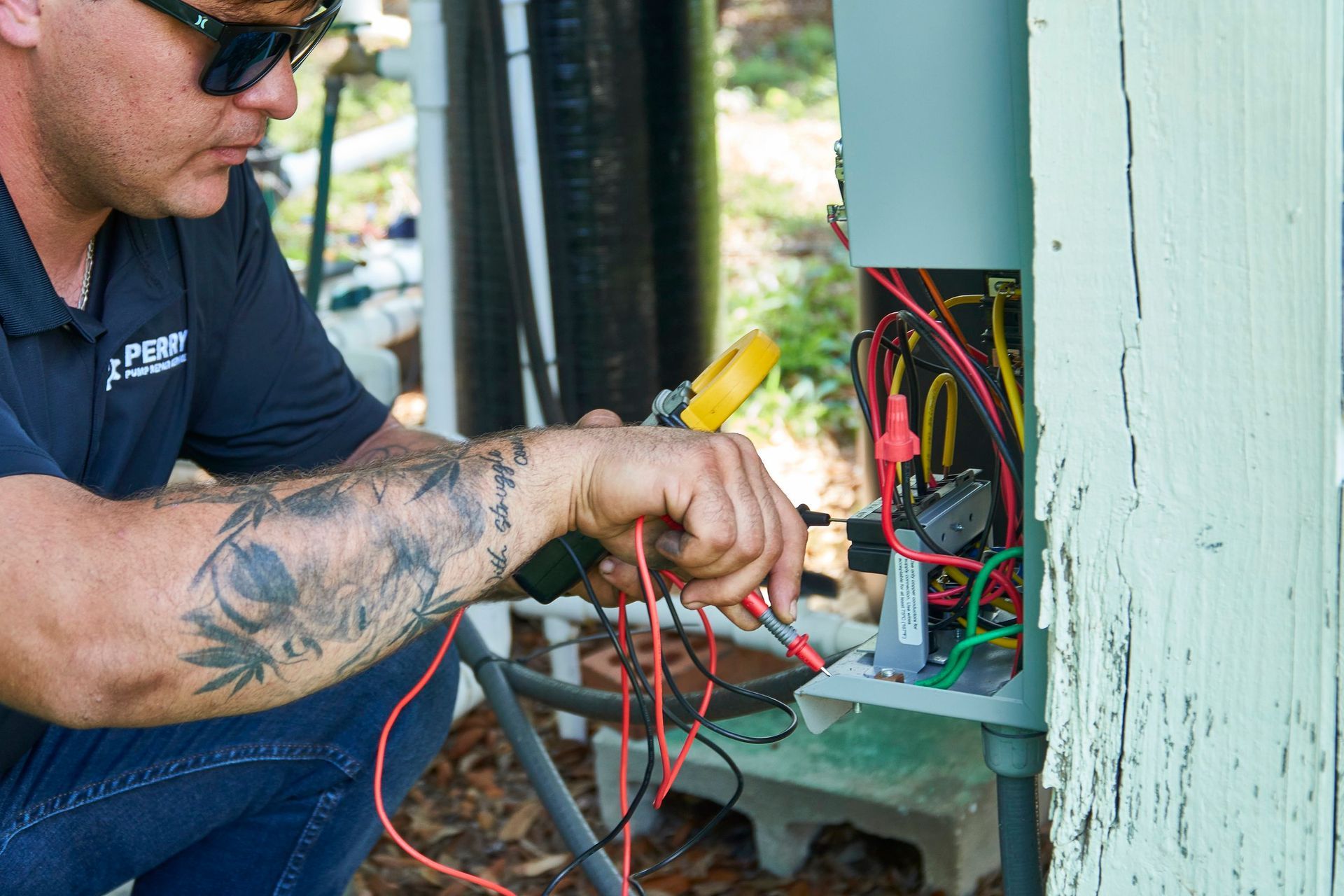 A man is working on an electrical box with a voltage meter.