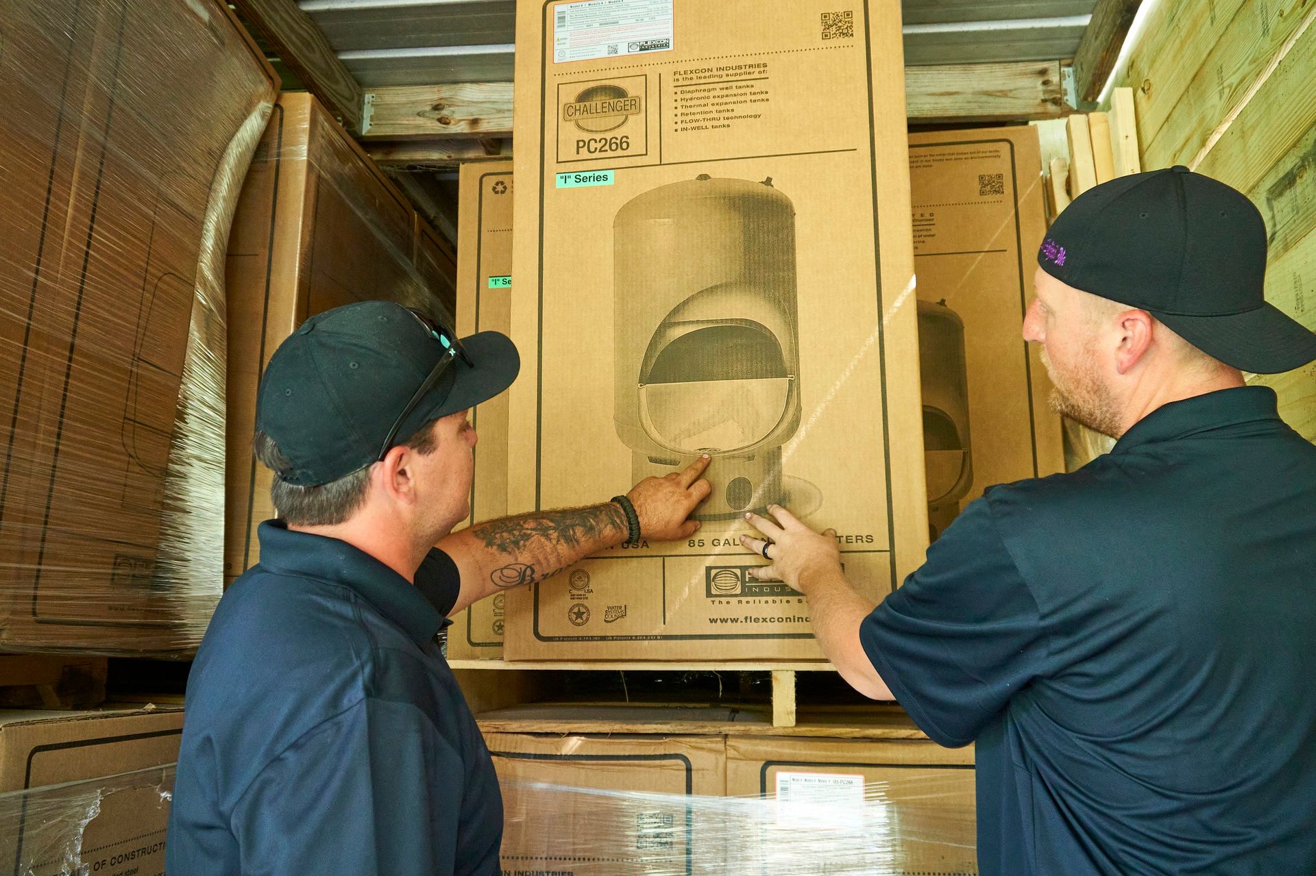 Two men are looking at a cardboard box in a truck.