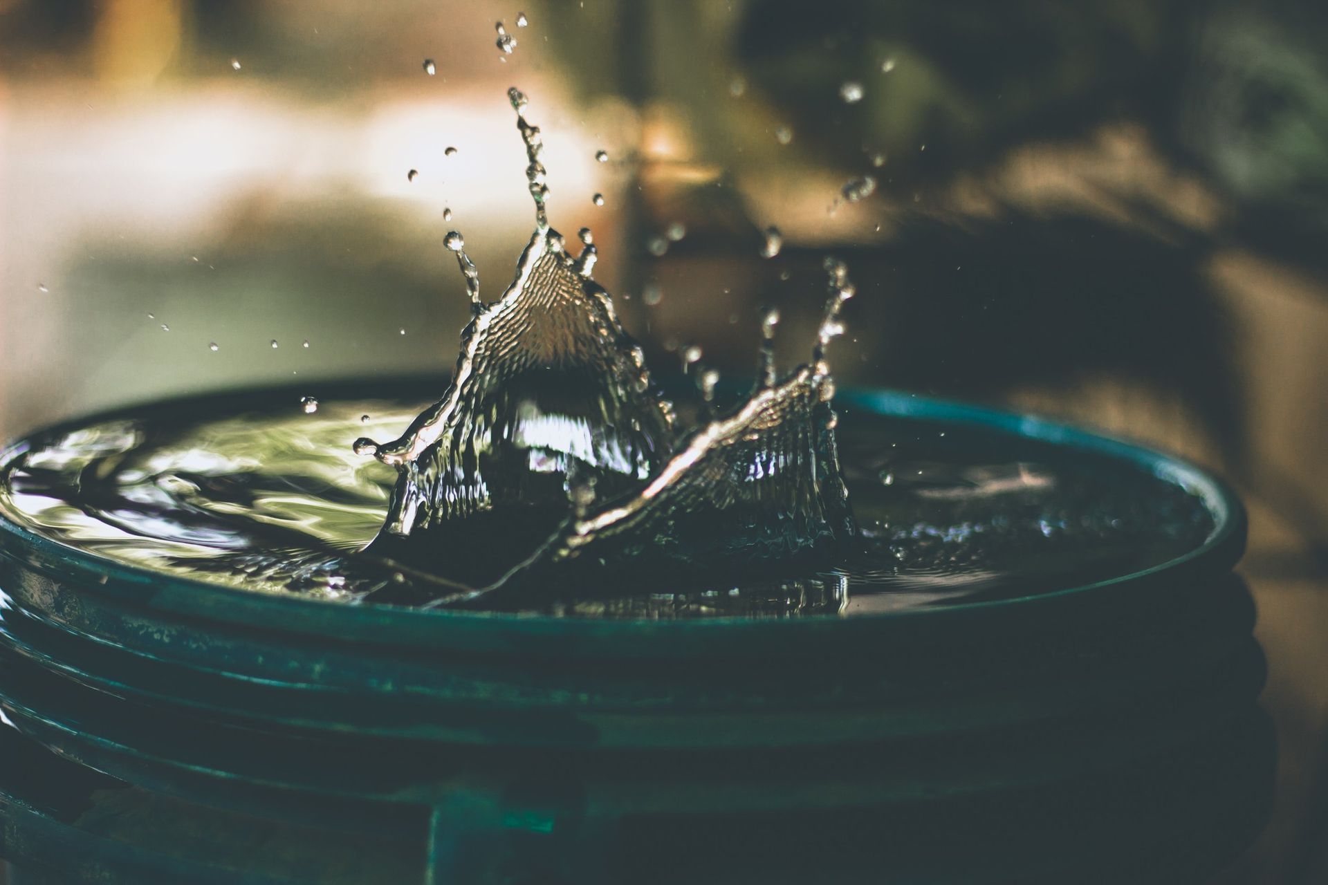 A close up of a bucket of water with water splashing out of it.