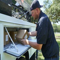 A man is putting a box in the back of a truck.