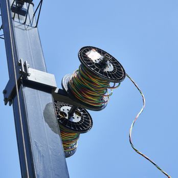 Three spools of wires are attached to a pole