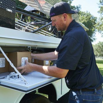 A man in a black shirt is loading boxes into the back of a truck