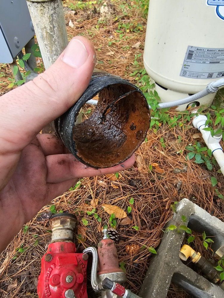 A person is holding a rusty pipe in their hand.