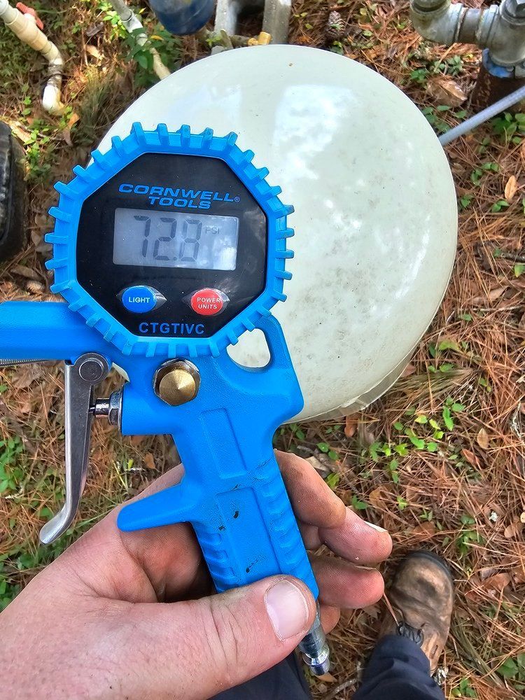 A person is holding a digital tire gauge that reads 128.7