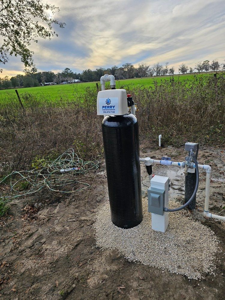 A water filter is sitting on top of a pile of gravel next to a field.