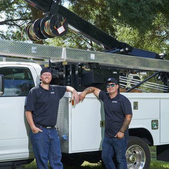 Two men are standing next to a utility truck.