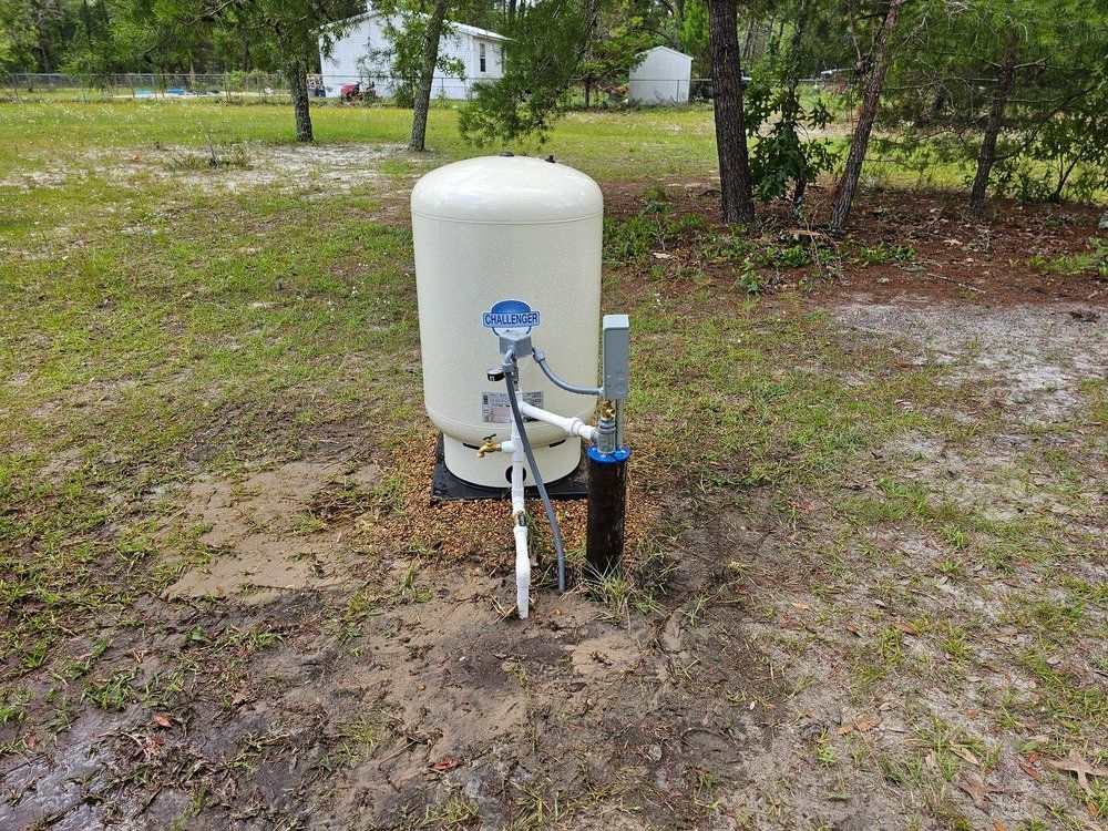 A water pump is sitting in the middle of a grassy field.