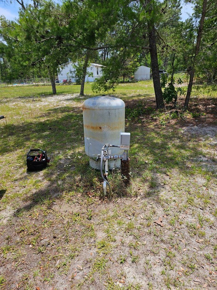 A large metal tank is sitting in the middle of a grassy field.