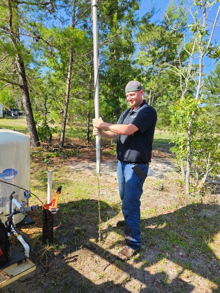 A man is standing in the grass holding a pole.