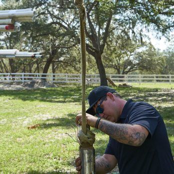 A man is working on a pipe in a field.