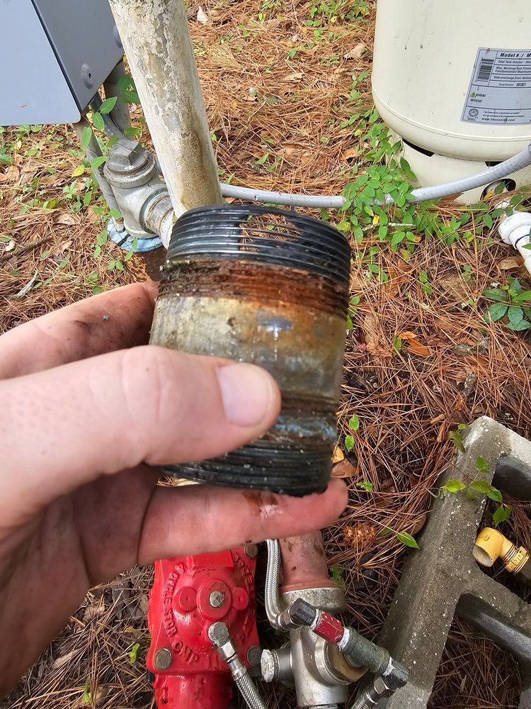 A person is holding a rusty pipe in their hand.