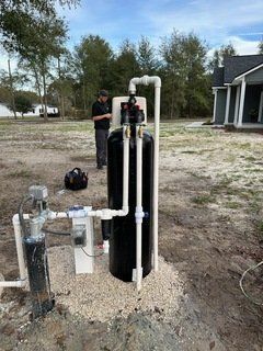 A man is standing next to a water filter in a field.