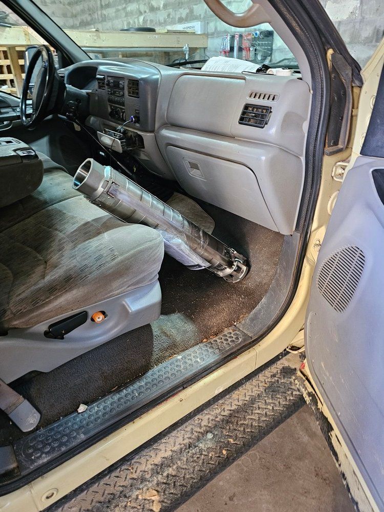 A yellow truck with a broken exhaust pipe in the back seat.