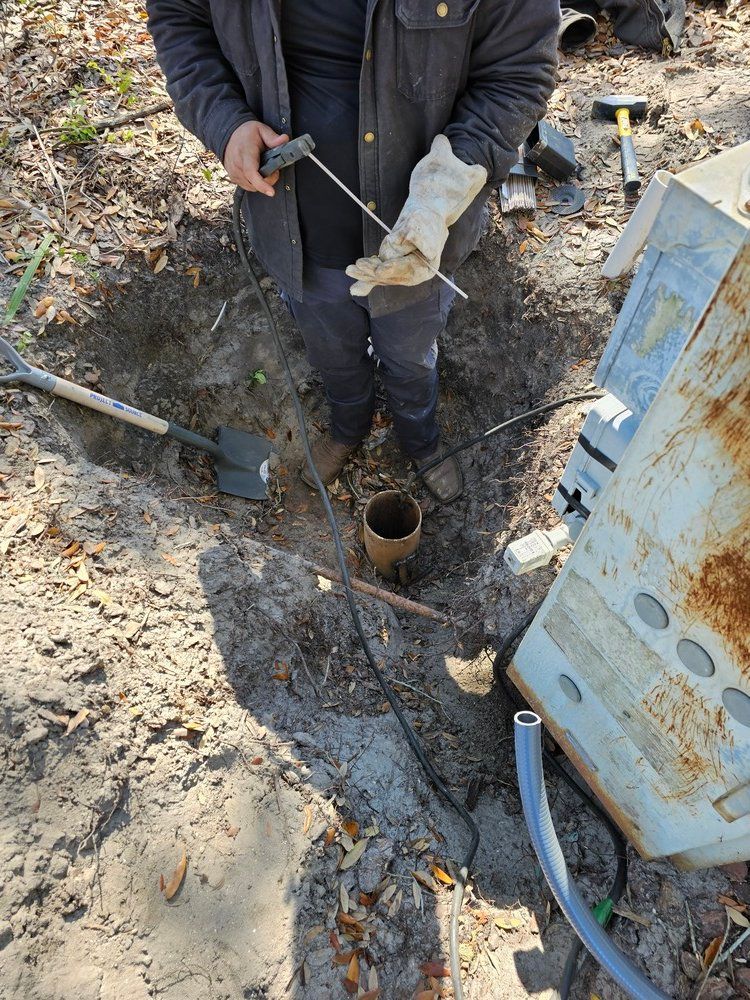 A man is standing in the dirt next to a rusty box.
