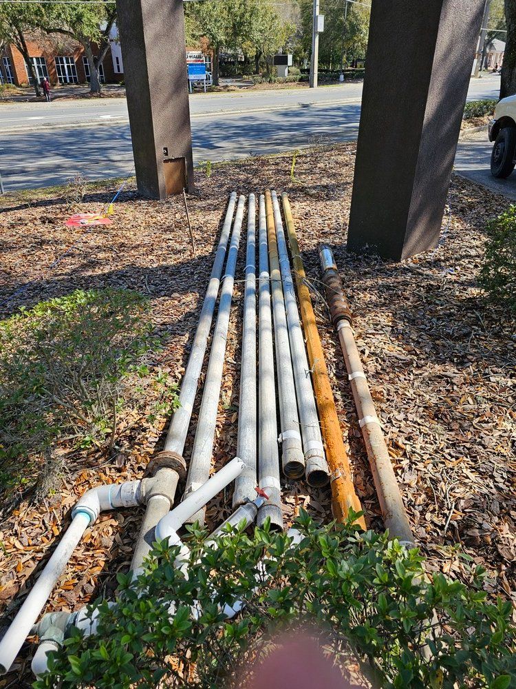 A bunch of pipes are sitting on the ground next to a tree.