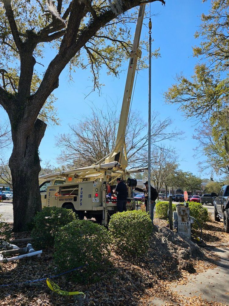 A man is working on a pole with a crane in a parking lot.