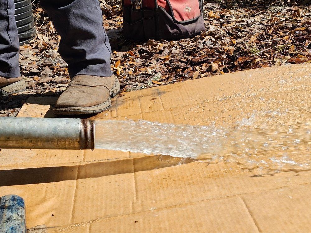 A person is standing next to a pipe with water coming out of it