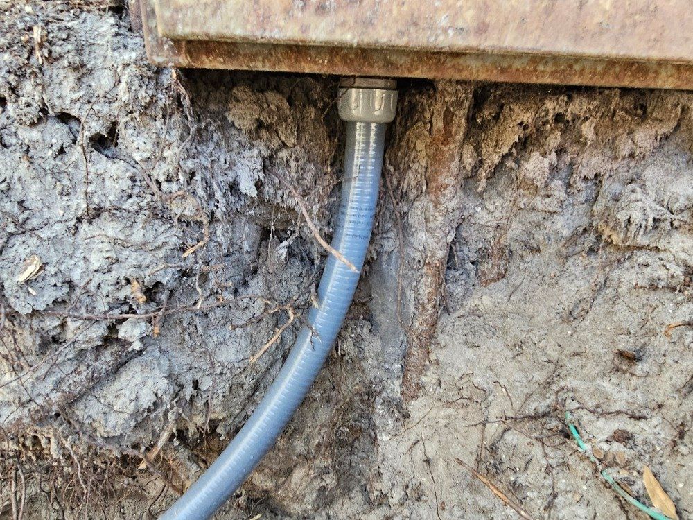A hose is connected to a metal pipe in the dirt.
