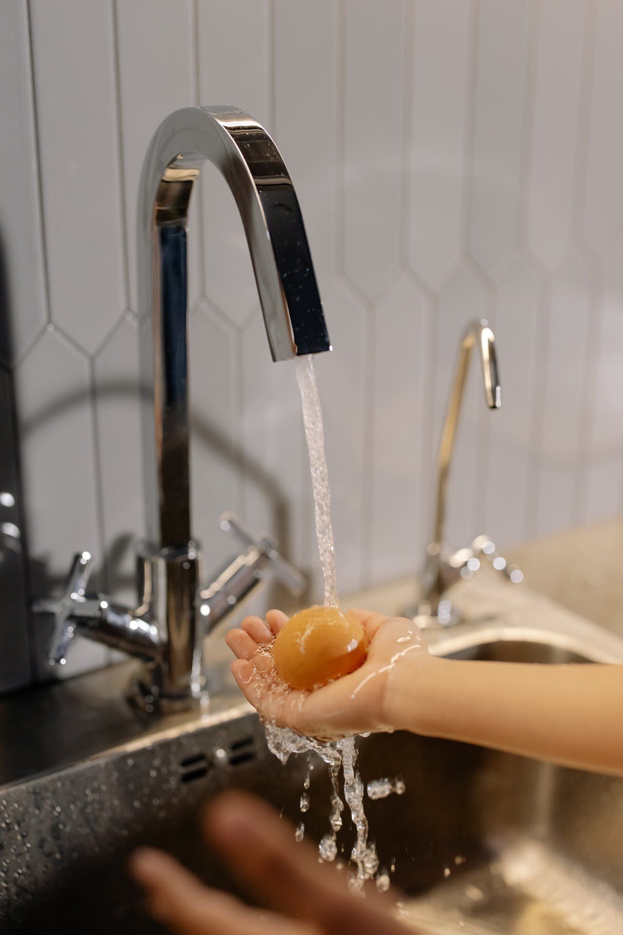 A person is washing their hands in a kitchen sink.