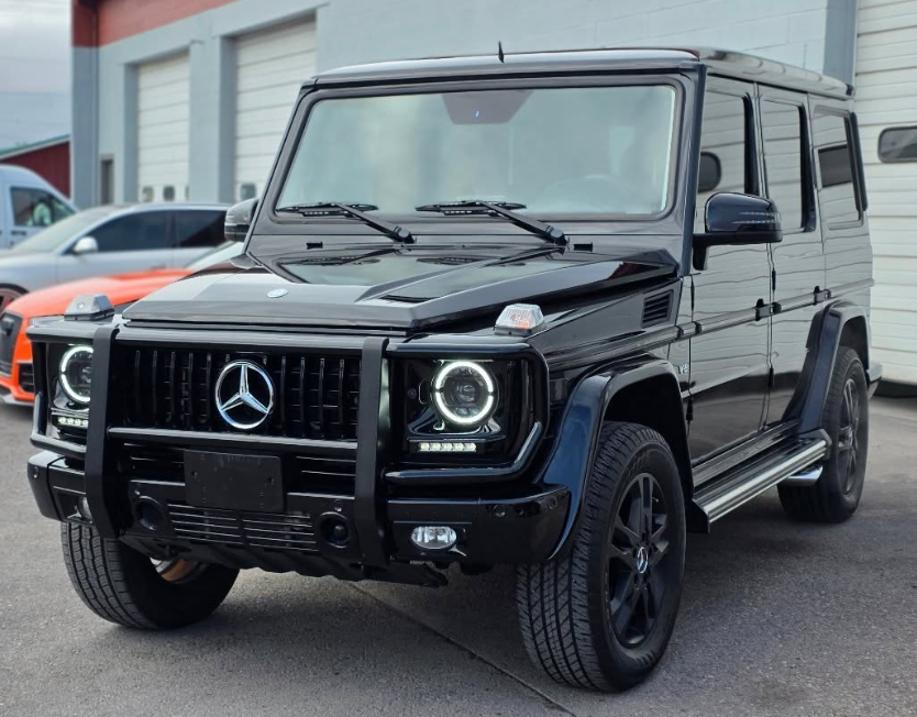 Black Mercedes G-Class SUV parked outside a building, front view.
