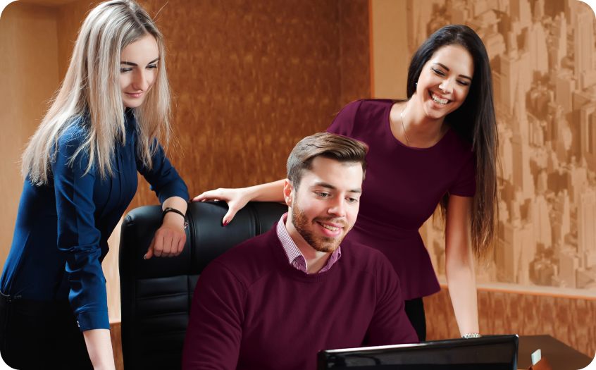 Um homem e duas mulheres estão olhando para a tela de um computador.