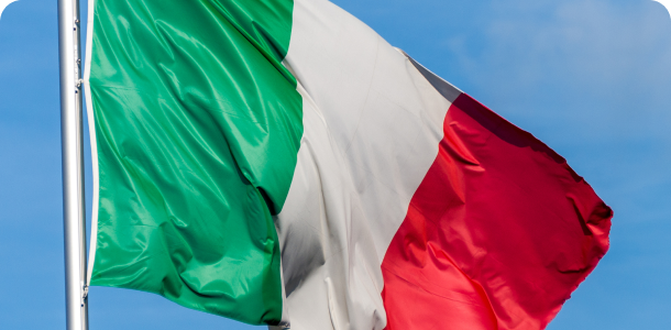 Uma bandeira italiana está balançando ao vento contra um céu azul.