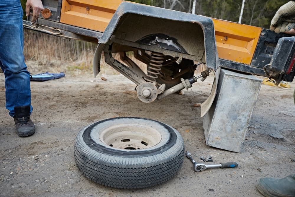 A man is changing a tire on a trailer. — Queensland Roadworthy Services In Southport, QLD