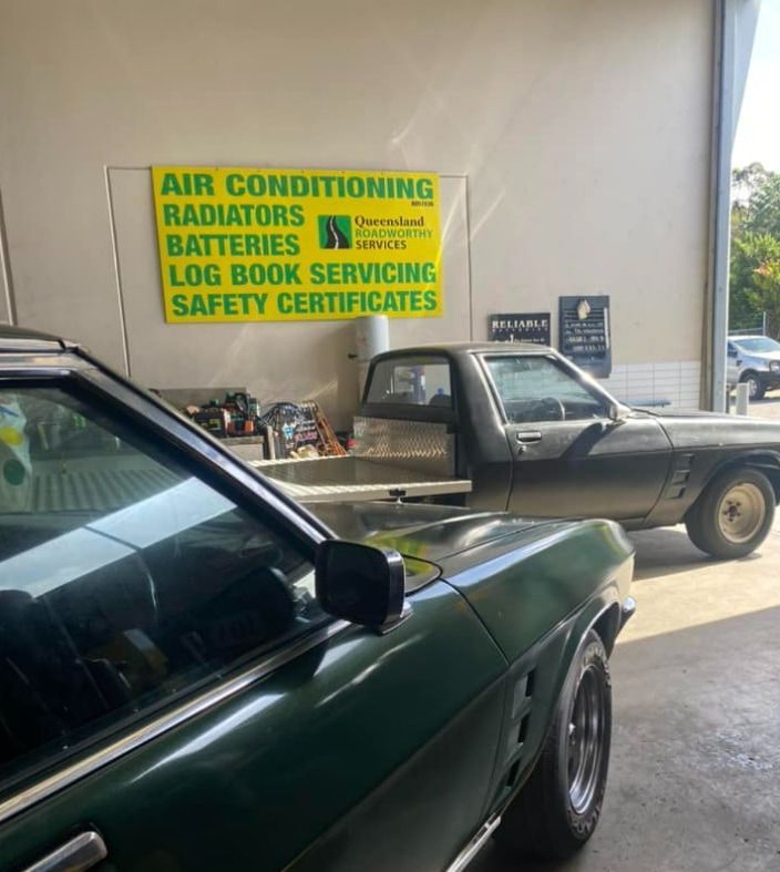 A Green Car is Parked in Front of a Sign — Queensland Roadworthy Services In Southport, QLD
