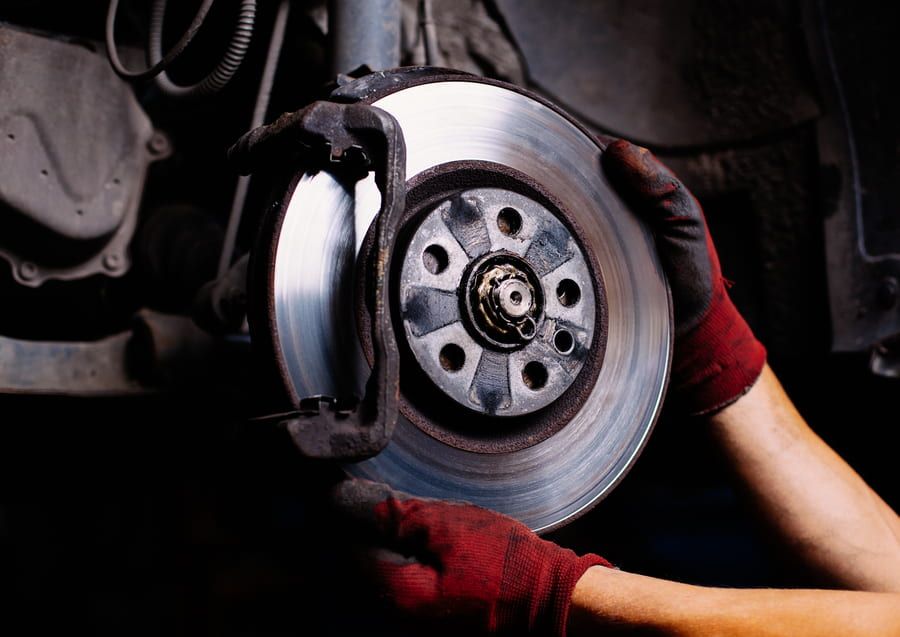 A Person is Fixing a Brake Disc on a Car — Queensland Roadworthy Services In Southport, QLD