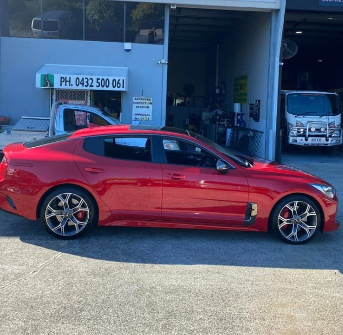 A Red Car is Parked in Front of a Building That Says Ph 043 500 061 — Queensland Roadworthy Services In Southport, QLD