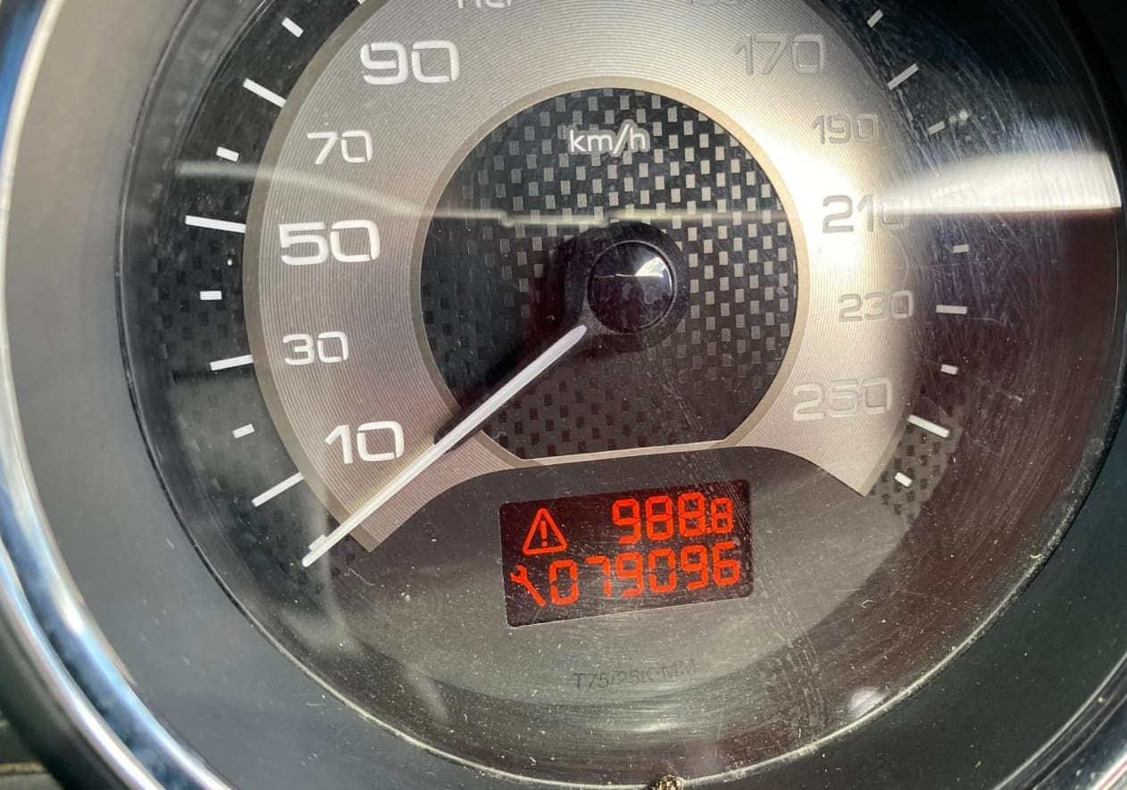 A Close Up of a Speedometer With a Warning Sign on It — Queensland Roadworthy Services In Southport, QLD