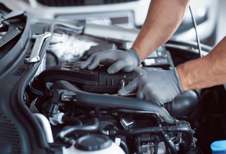 A Man is Working on the Engine of a Car — Queensland Roadworthy Services In Southport, QLD