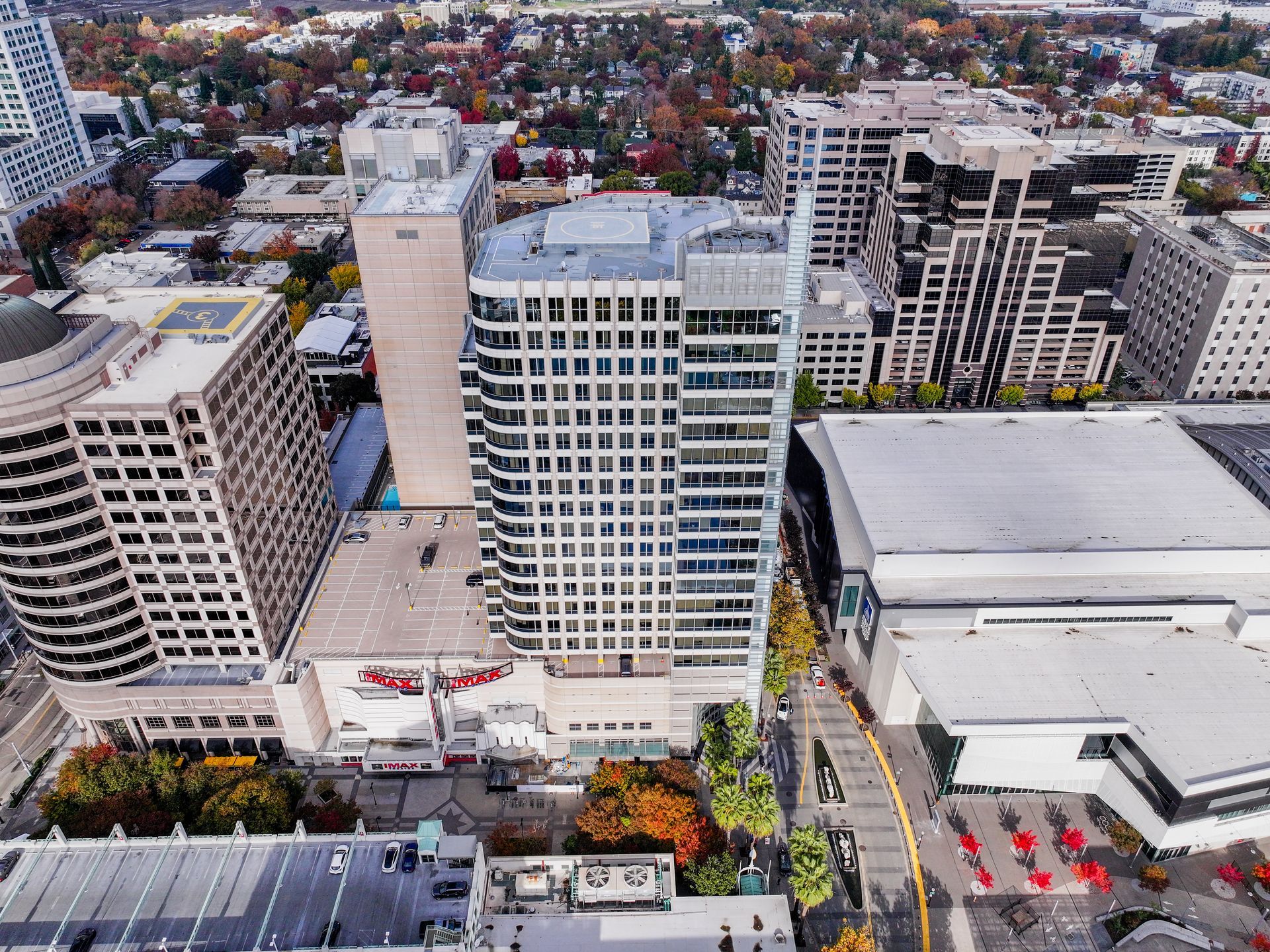 Aerial view of a city center with various tall buildings and autumnal trees.