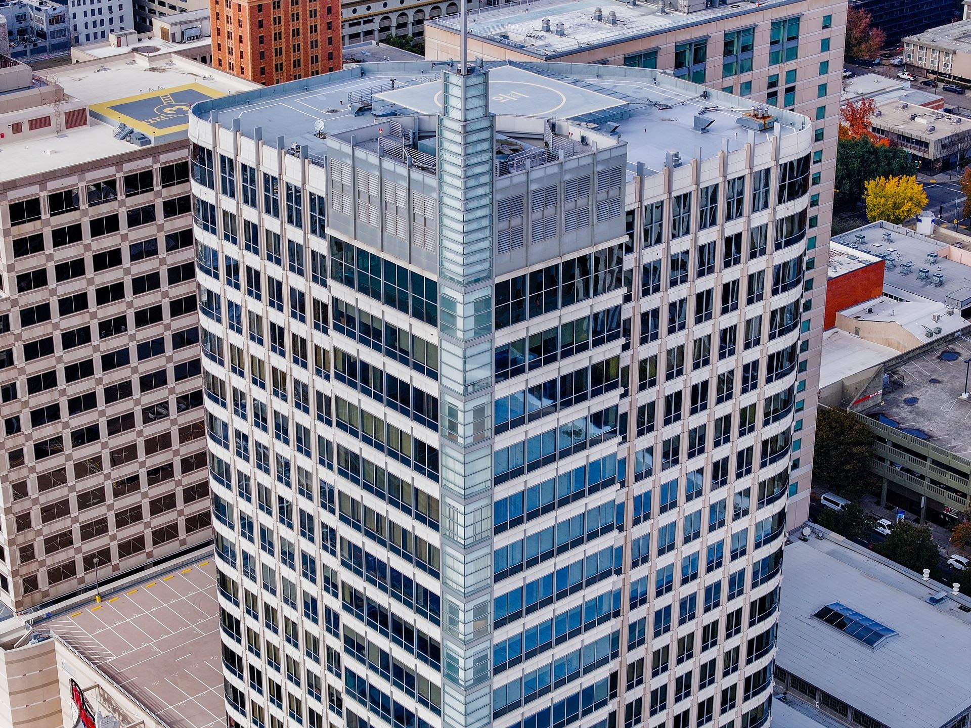 High-rise office building with blue-tinted windows, a flat roof, and a glass tower on top.
