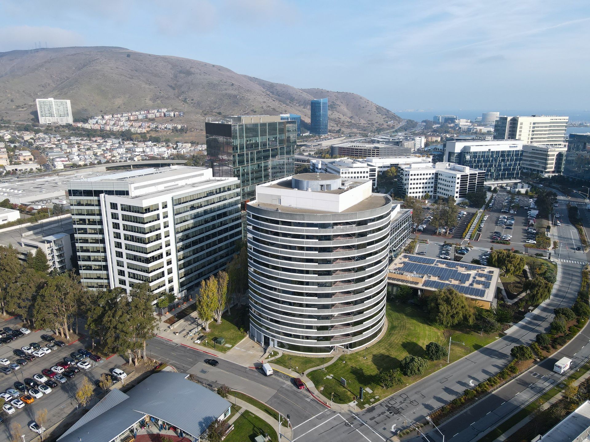 Office buildings and cityscape with a mountain backdrop under a partly cloudy sky.
