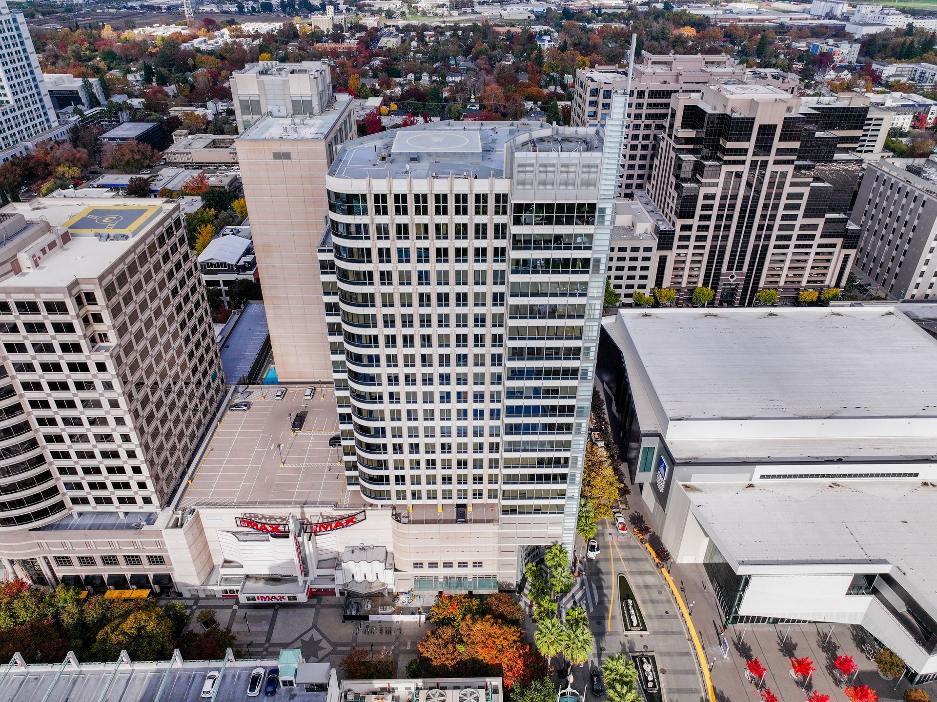 Aerial view of tall buildings in a city, including a white office building and theater with a red sign.