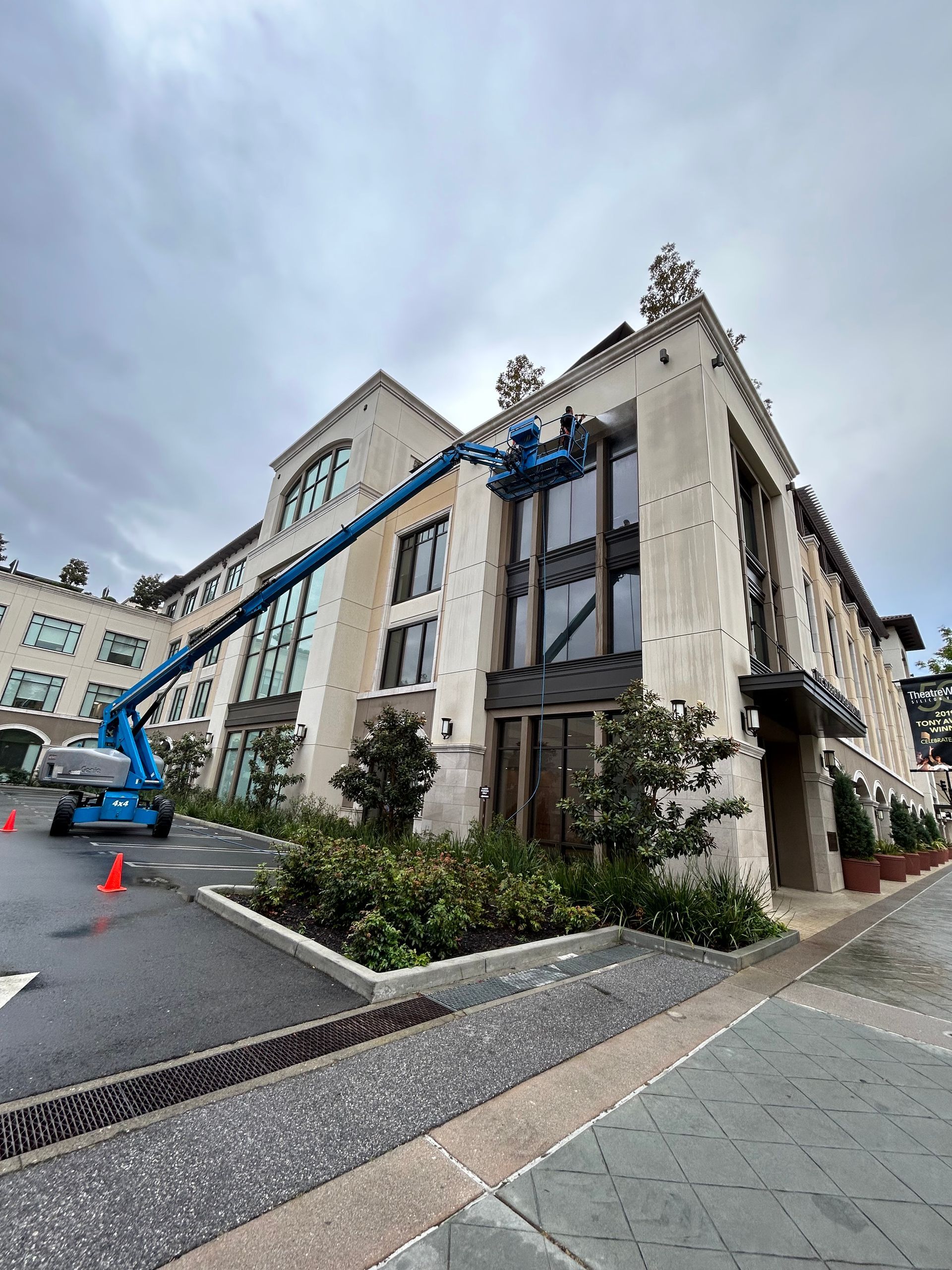 A blue lift in front of a stone building, possibly under construction or repair, on a cloudy day.