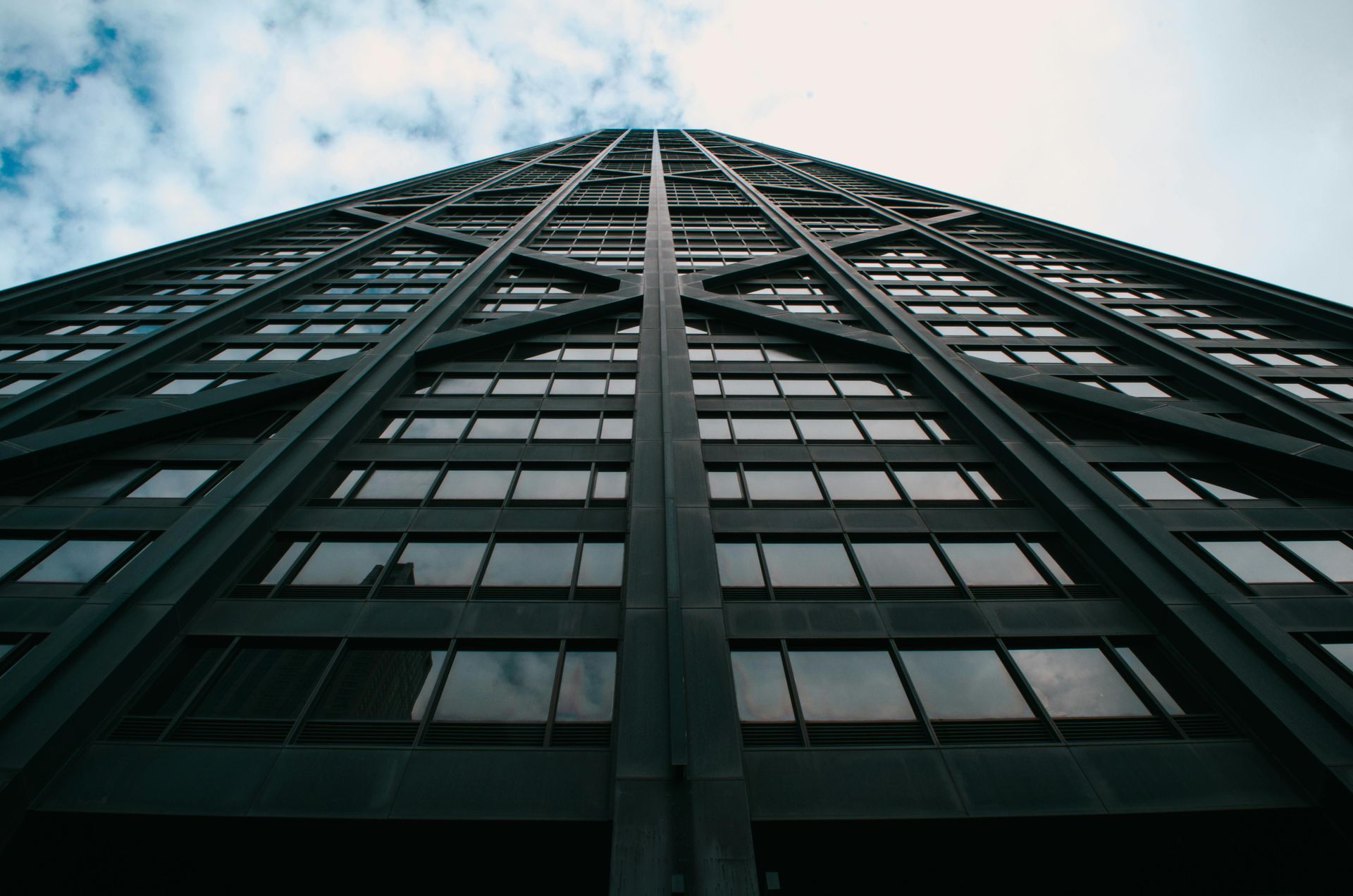 Tall, dark skyscraper against a cloudy sky, seen from a low-angle perspective.