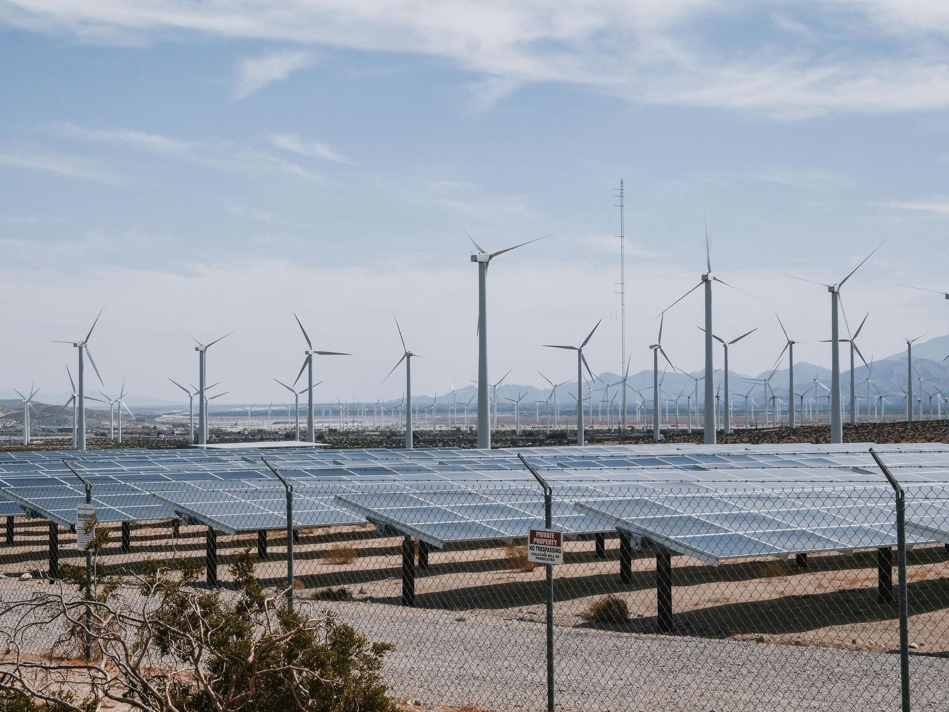 Solar panels and wind turbines in a desert landscape, generating renewable energy.