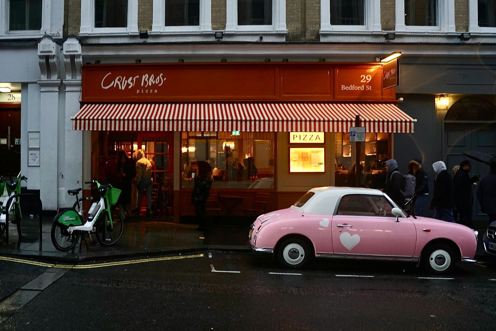 Modern high-rise building with glass and balconies next to an older, light-colored building under a blue sky.