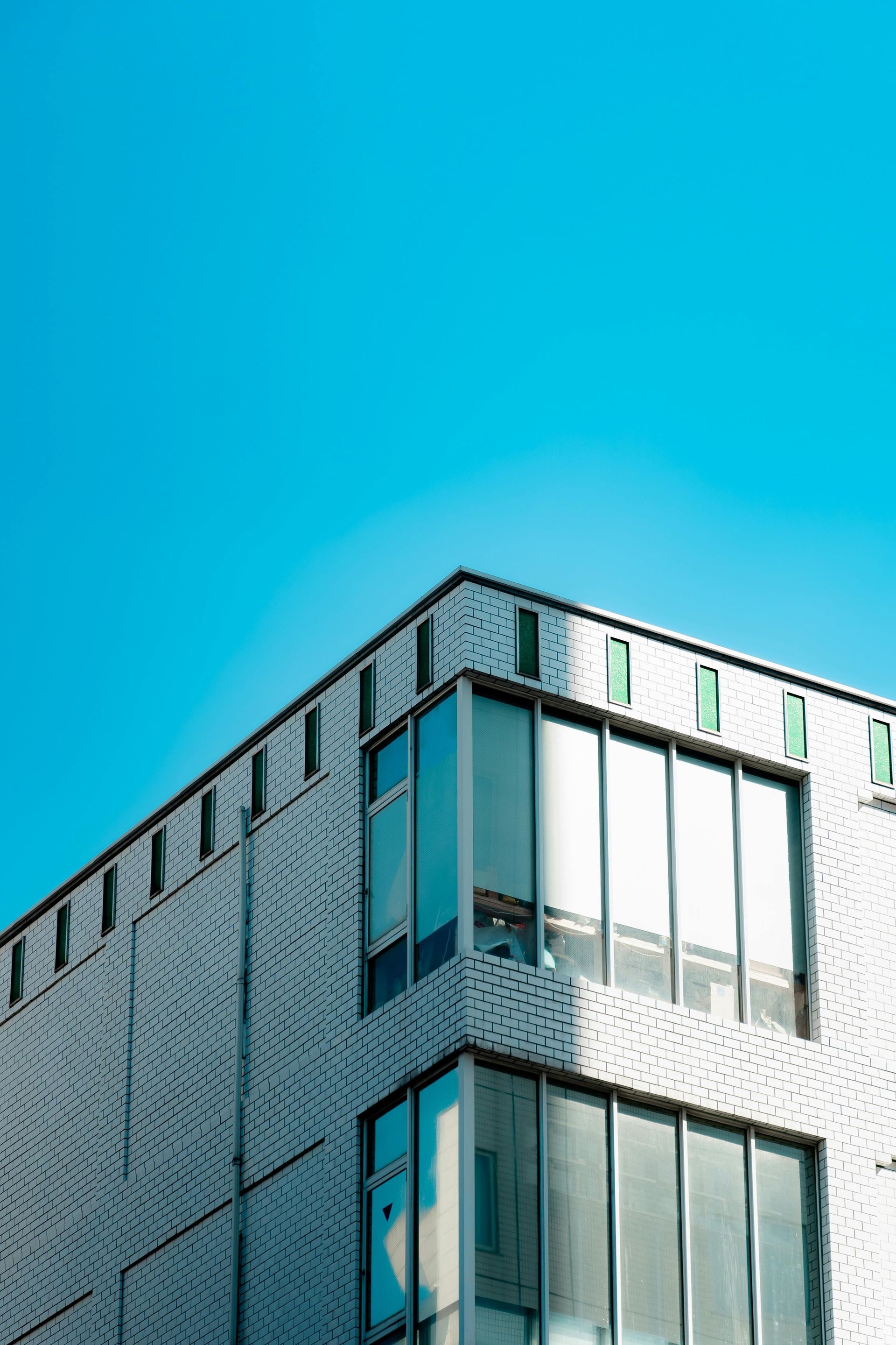 White building with large windows against a bright blue sky.