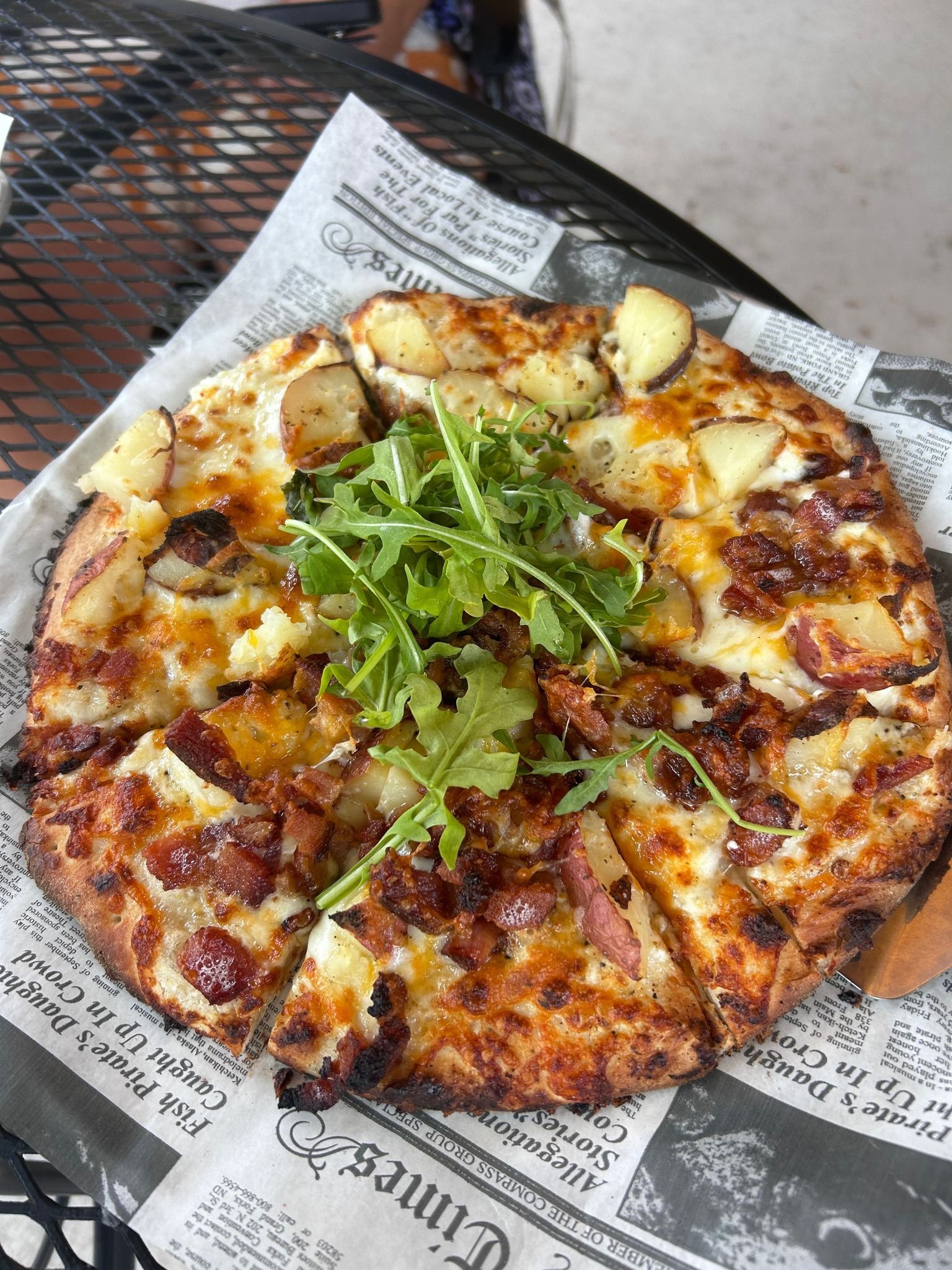 A grilled cheese sandwich with pepperoni and cheese is cut in half on a checkered napkin.
