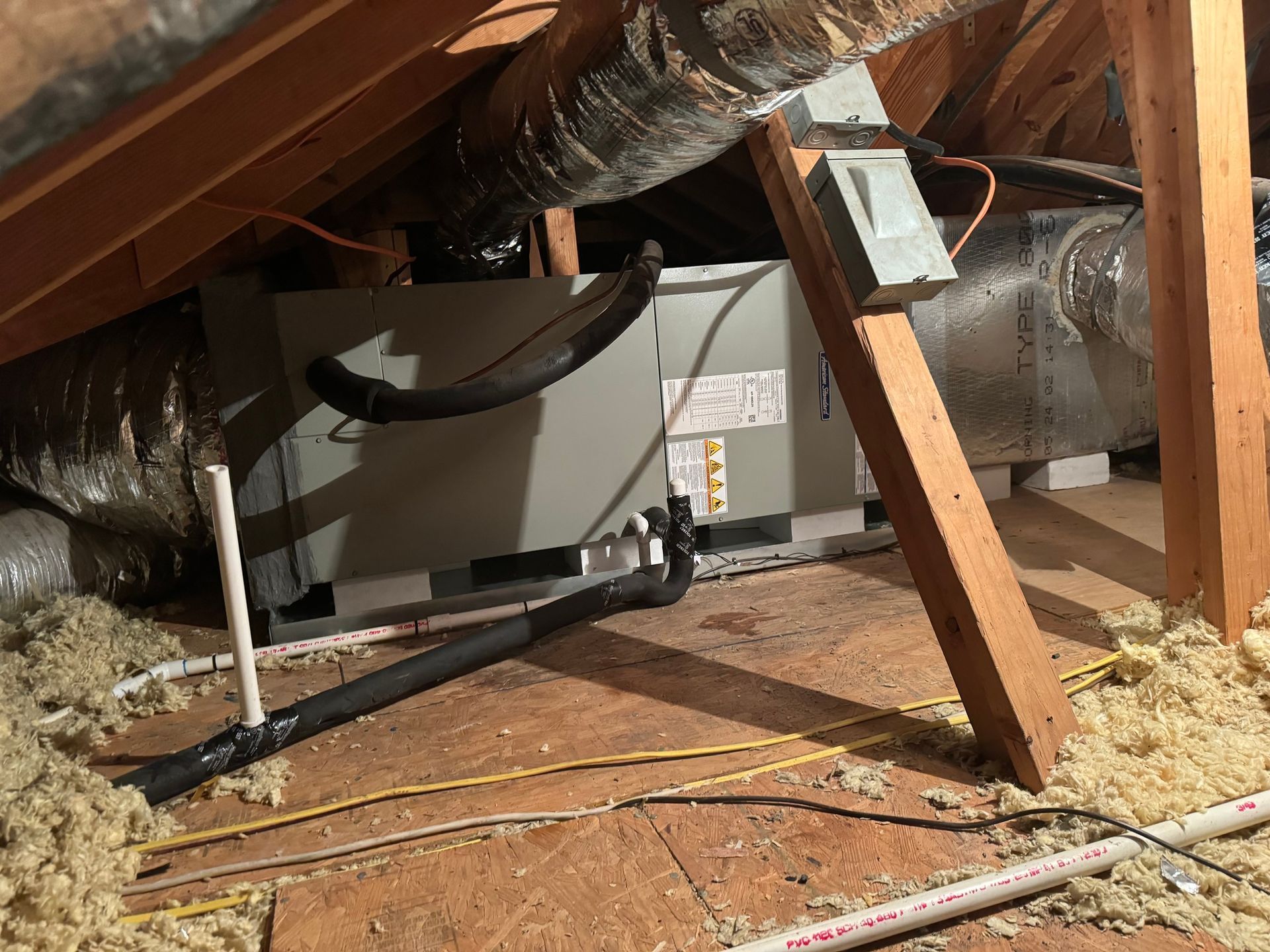 An air conditioner is sitting in the attic of a house.