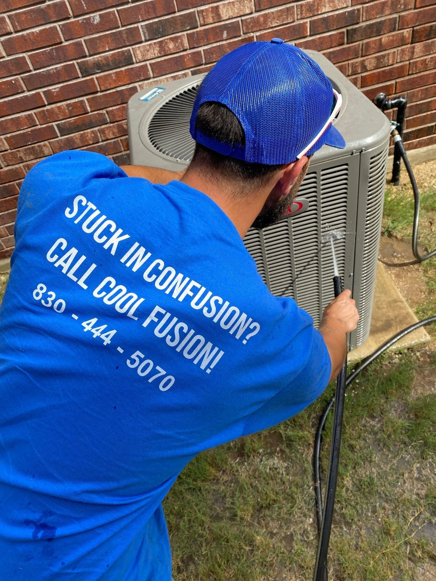 A man in a blue shirt is working on an air conditioner.