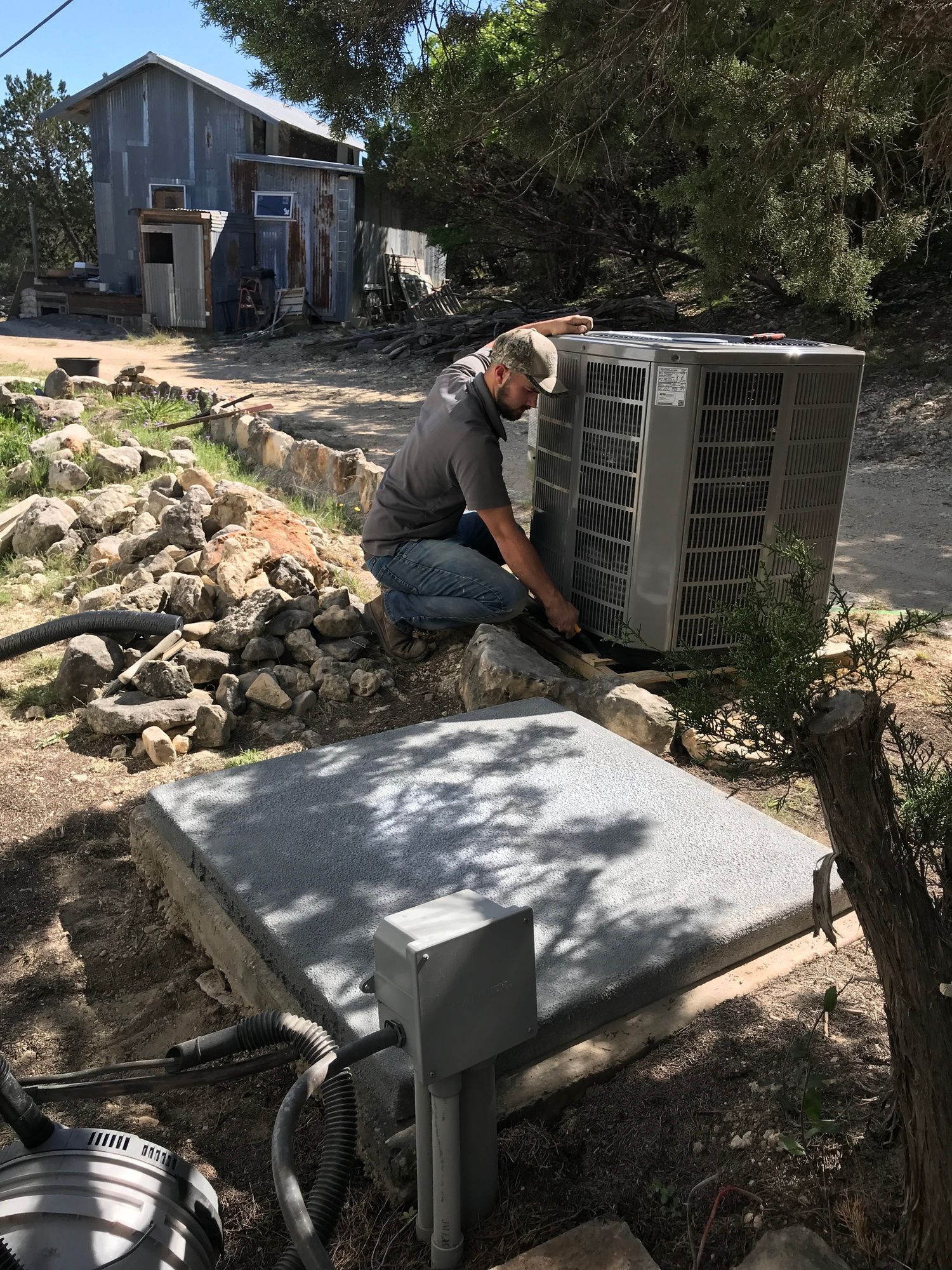 A man is working on an air conditioner outside of a house.